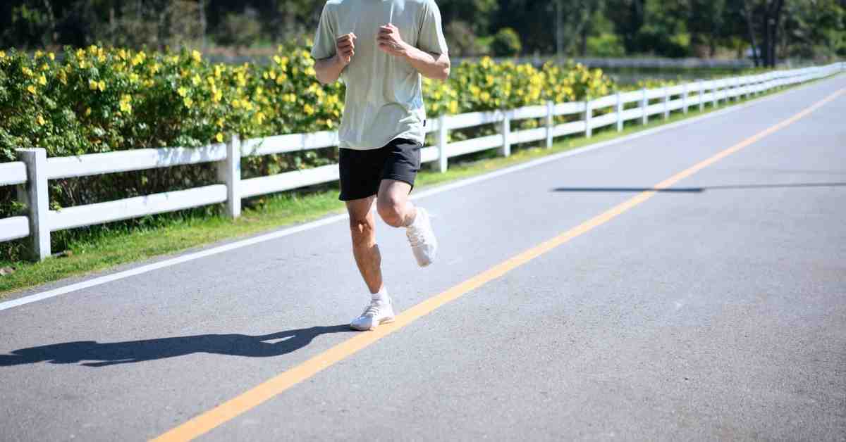 coureur homme courant sur route avec tenue de running respirante pour éviter les frottements pendant la course à pied